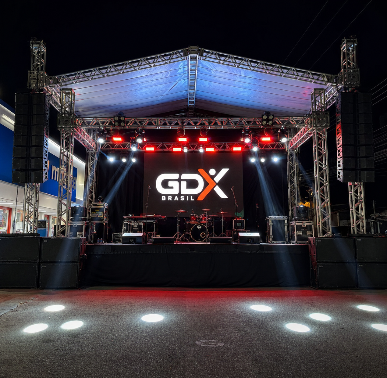 Palco de evento à noite montado pela GDX Brasil, com painel de LED exibindo o logo GDX, treliças de estrutura, line arrays de som e iluminação cênica.